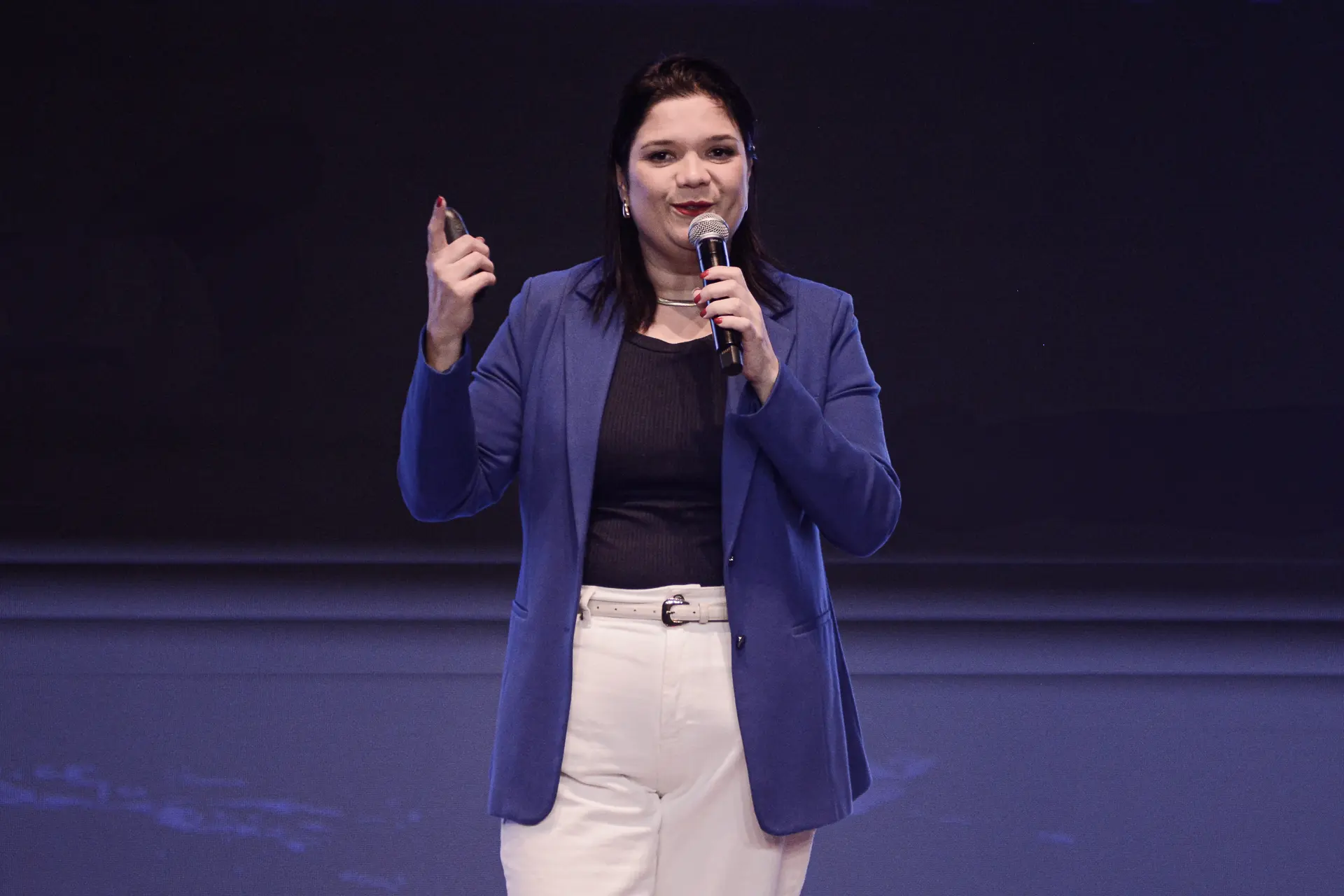 Palestrante discursando com microfone em evento corporativo